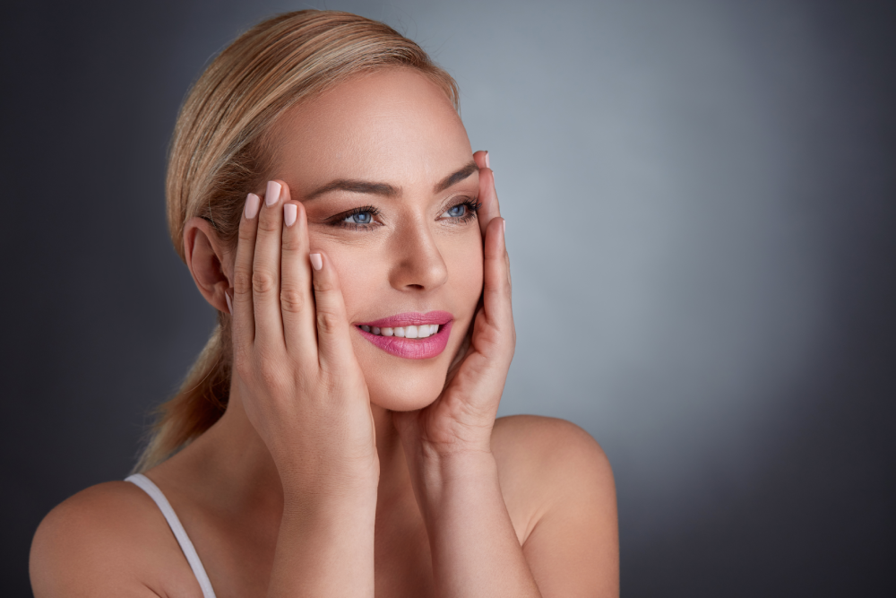 Woman gently touching her face, showing results of dermal filler.