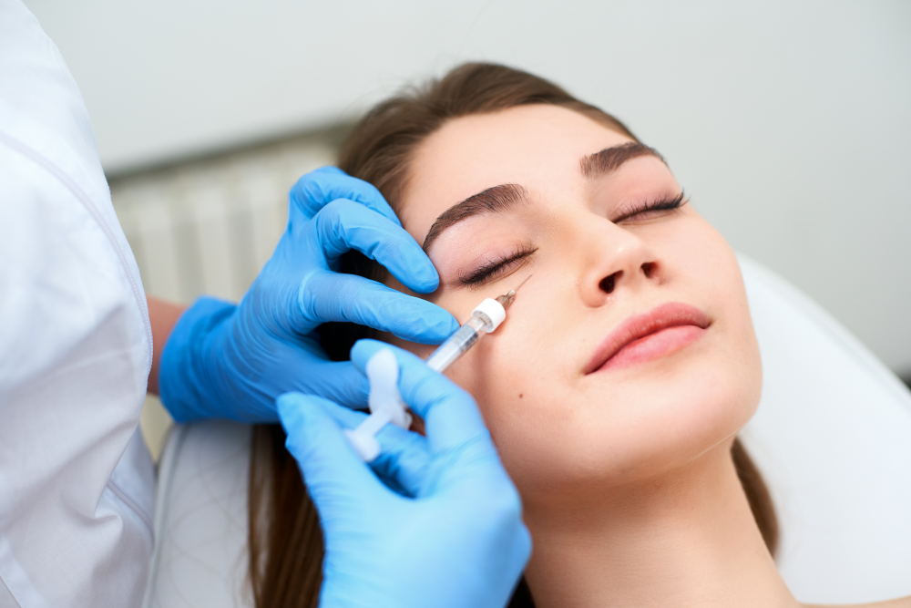 Close-up of a dermal filler injection under a woman’s eye during a treatment session.